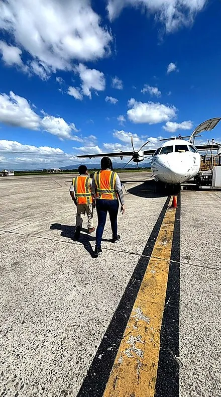 Personal con chalecos reflectivos caminando en la plataforma de un aeropuerto hacia un avión